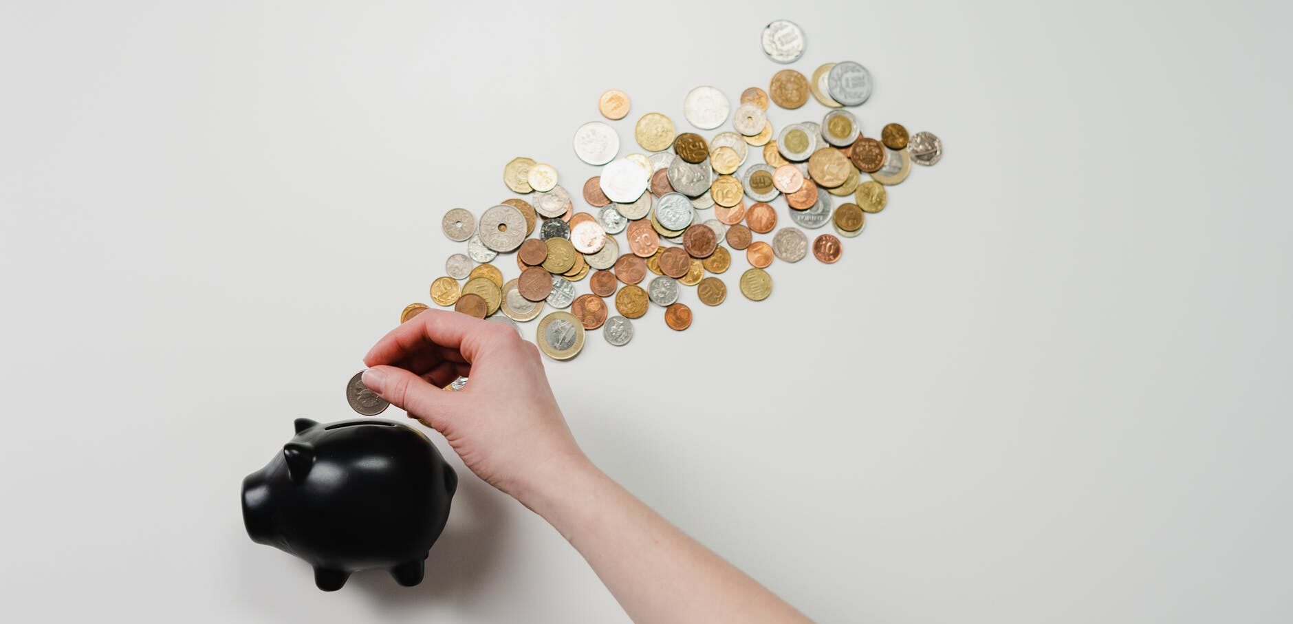 person putting coin in a piggy bank